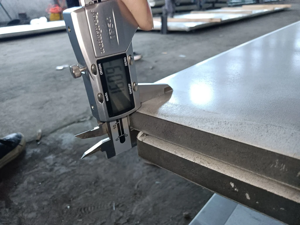 Inspector checking electrical steel sheet width and dimensions before shipment