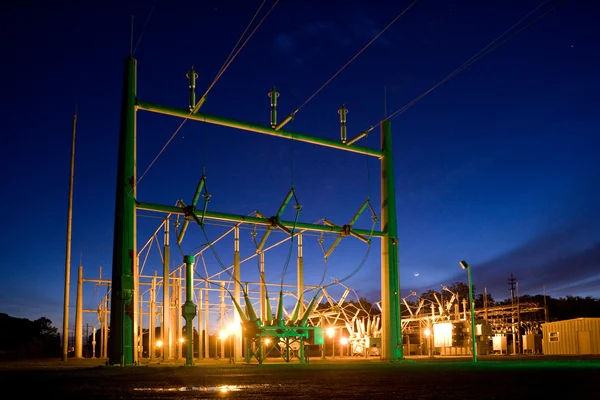 Electrical substation switchyard with transformer equipment and transmission lines at dusk