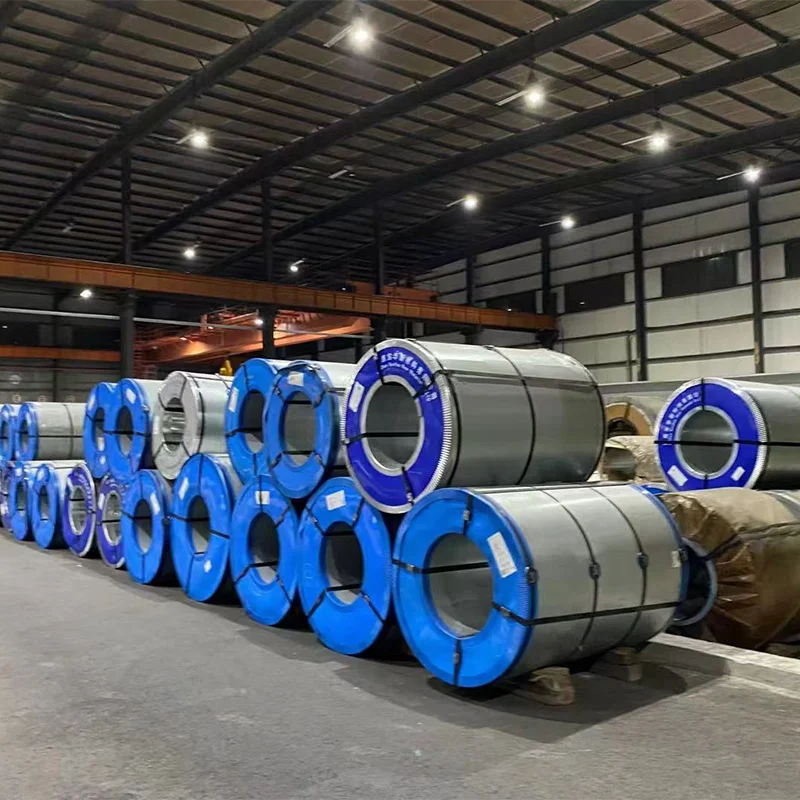 Warehouse interior with overhead crane and rows of blue-edged and kraft-wrapped electrical steel coils staged for slitting
