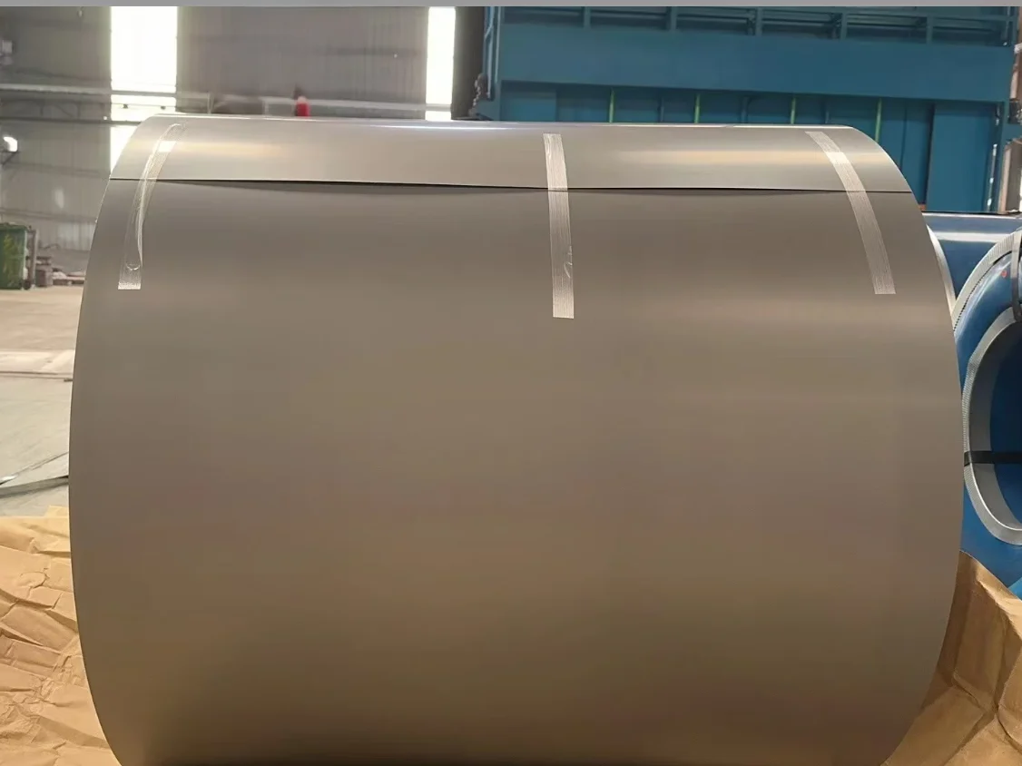 A grain-oriented electrical steel coil showing the wound laminated edge, beside a second coil banded with adhesive strips on a workshop floor