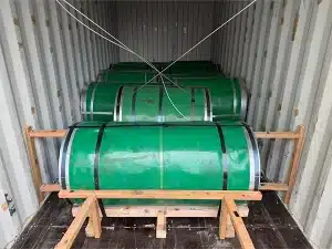 Interior of a 20ft shipping container loaded with green-wrapped CRGO electrical steel coils standing on end, braced with wooden cradle dunnage