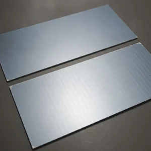 Two grain-oriented electrical steel samples, top with a plain coating, bottom with fine transverse laser scribe lines
