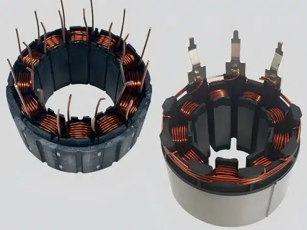 Close-up of a small motor stator core with copper windings wrapped around laminated silicon steel poles