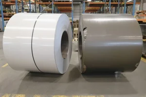 Two grain-oriented electrical steel coils side by side, one with a clean bright mill edge and one with a darker oiled and edge-damaged surface