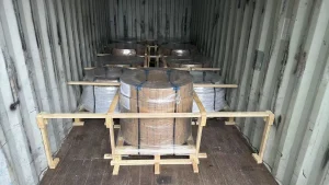 Slit CRGO strip coils stood eye-vertical inside a shipping container, stretch-wrapped and braced with a timber dunnage frame
