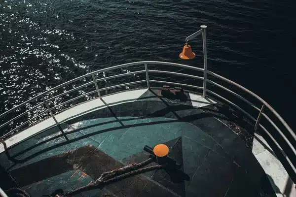 Ship's bow deck with metal railing over open seawater