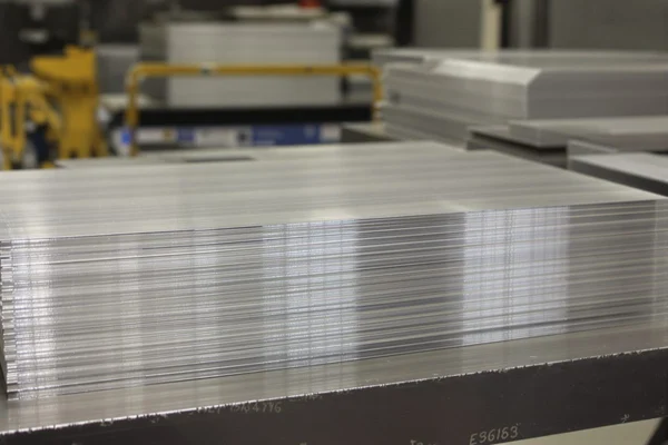 A stack of cut grain-oriented electrical steel transformer core laminations on a workbench