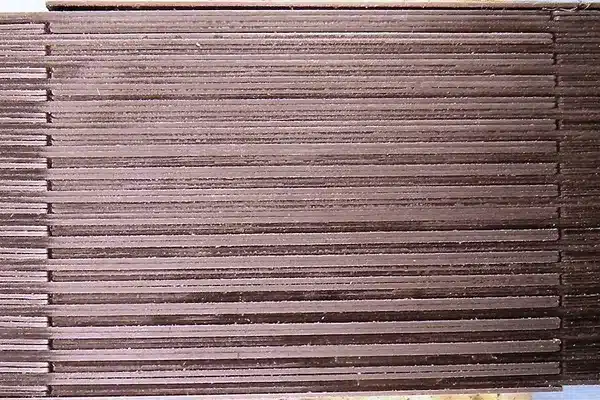 Edge view of interleaved E and I transformer laminations stacked into a core, showing the thin individual steel sheets