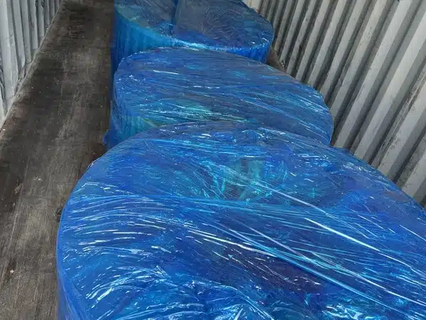 Nahaufnahme von blau stretchwickelten Längsteilspulen aus Siliziumstahl entlang eines Containerbodens